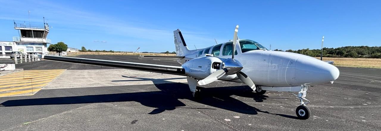 Avion bimoteur du Saumur Air Club sur le tarmac, devant la tour de contrôle