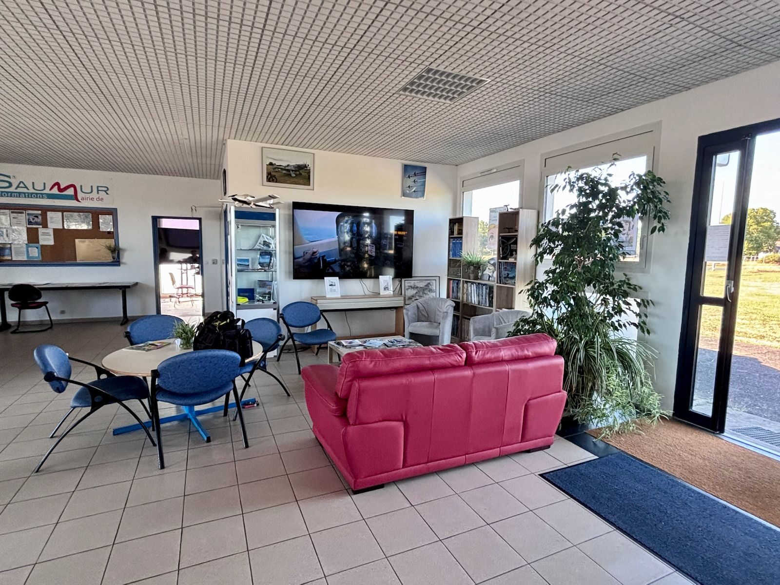 Le salon du club house, avec télévision, bibliothèque et vue sur la piste